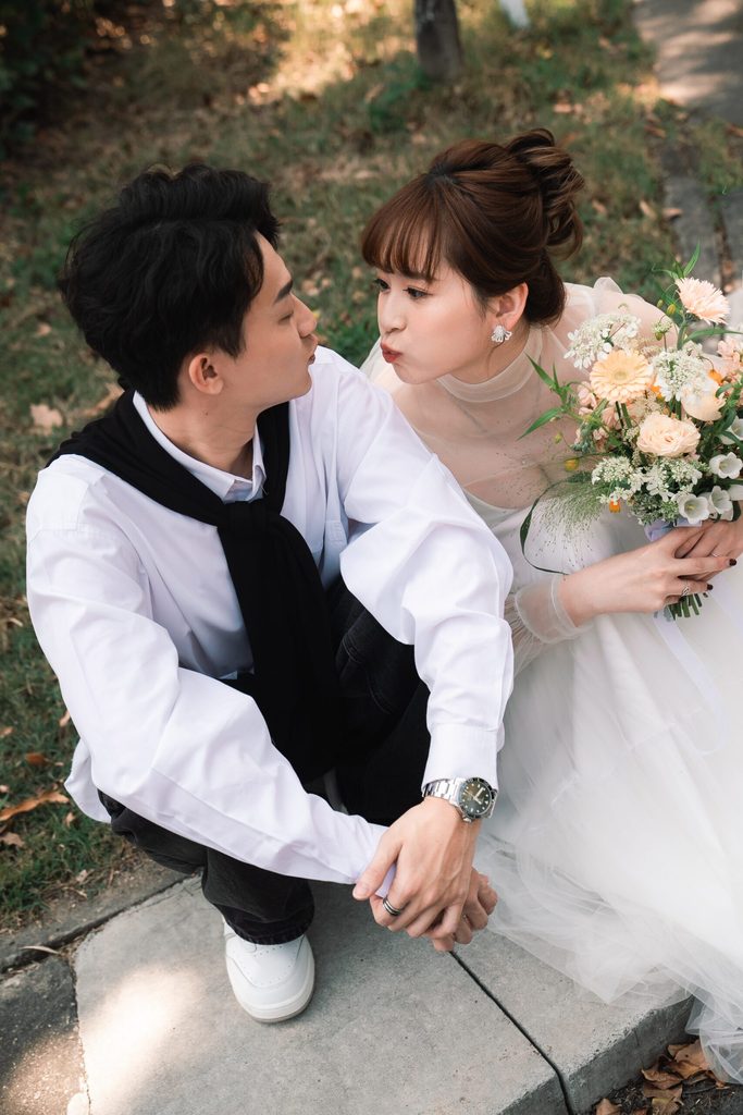 日系清新風輕婚紗照，新人坐在路邊互動，新娘手捧鮮花