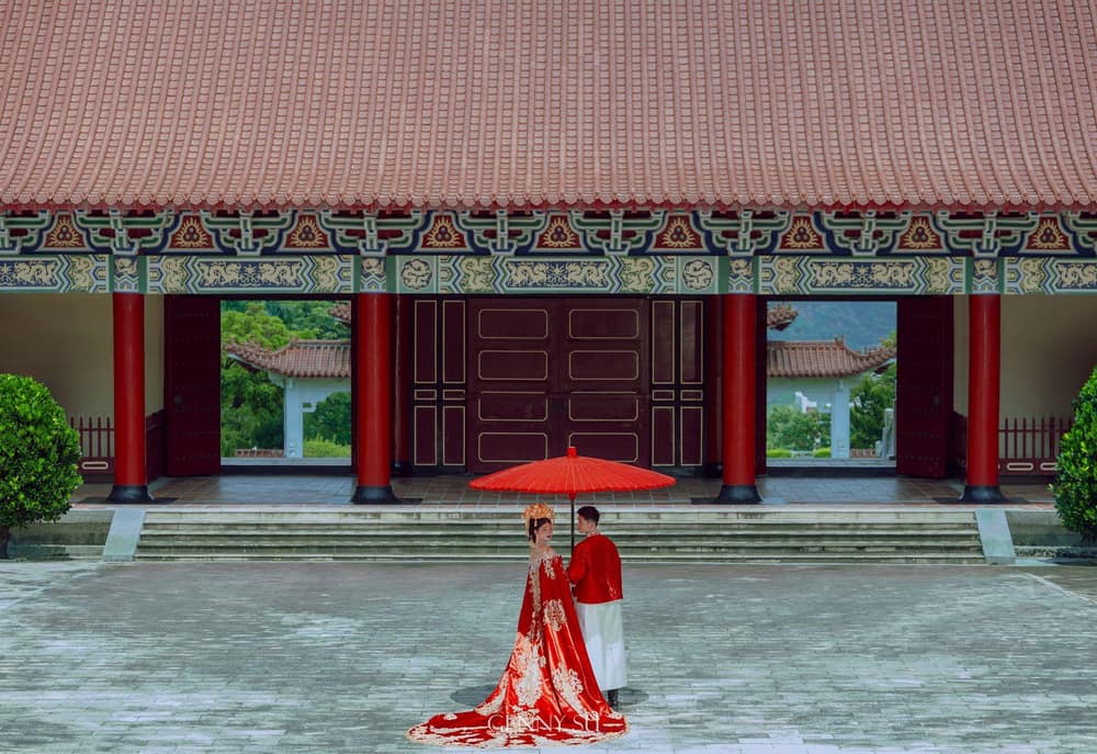新中式復古風婚紗照，新人撐紅傘站在宮殿式建築前